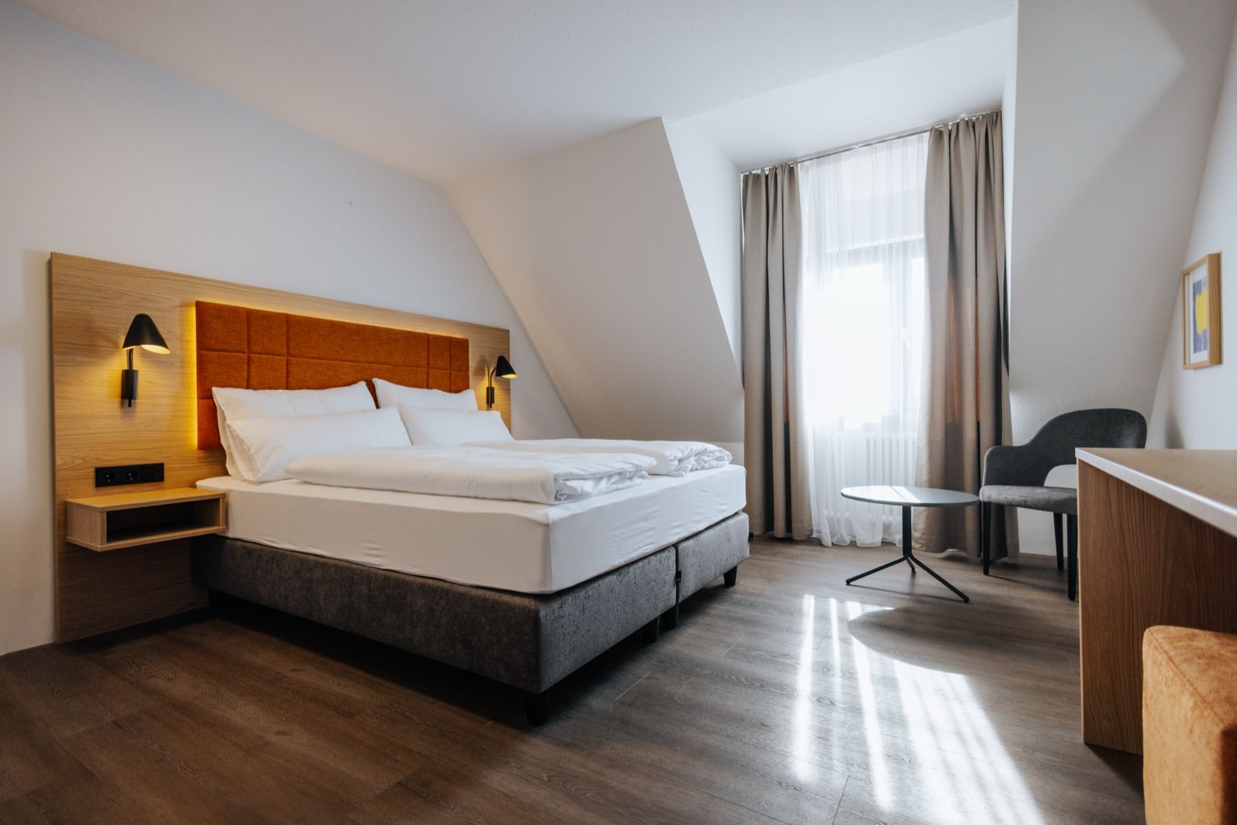 Attic room at Hotel zwölf87 traumwerk with a wooden headboard and sloping ceiling