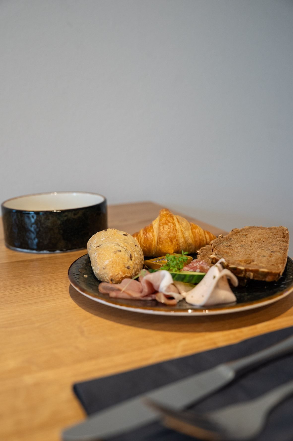 Frühstücksteller mit Croissant, Brötchen und Schinken im mundwerk