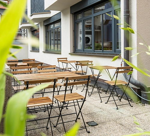 Innenhof des Hotels zwölf87 – Traumwerk in Ravensburg mit mehreren Tischen und Stühlen