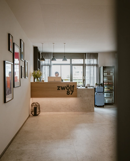 Rezeption im Hotel zwölf87 – Traumwerk in Ravensburg mit einem Mitarbeiter hinter der Empfangstheke